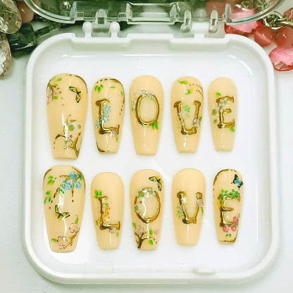 Nail art set with 'LOVE' design on pastel yellow nails in a white case.