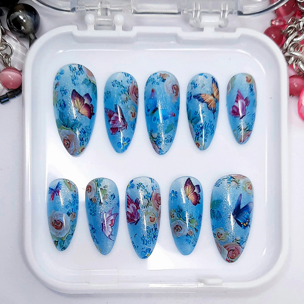 Set of blue butterfly and floral nail art designs in a white case.