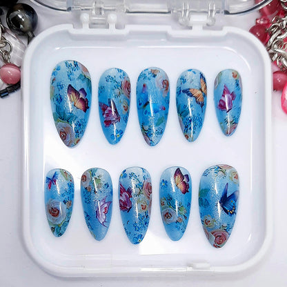 Set of blue butterfly and floral nail art designs in a white case.