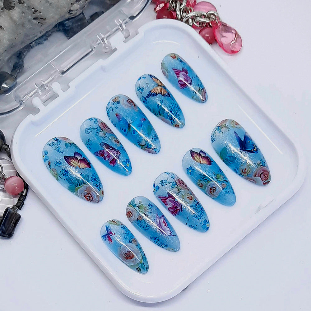 Very beautiful shimmering blue semi-sheer press on nails with flowers and butterflies. Finished in gloss top coat.