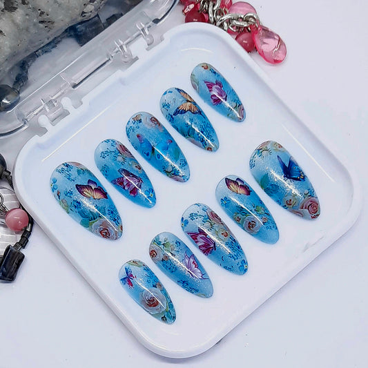 Very beautiful shimmering blue semi-sheer press on nails with flowers and butterflies. Finished in gloss top coat.