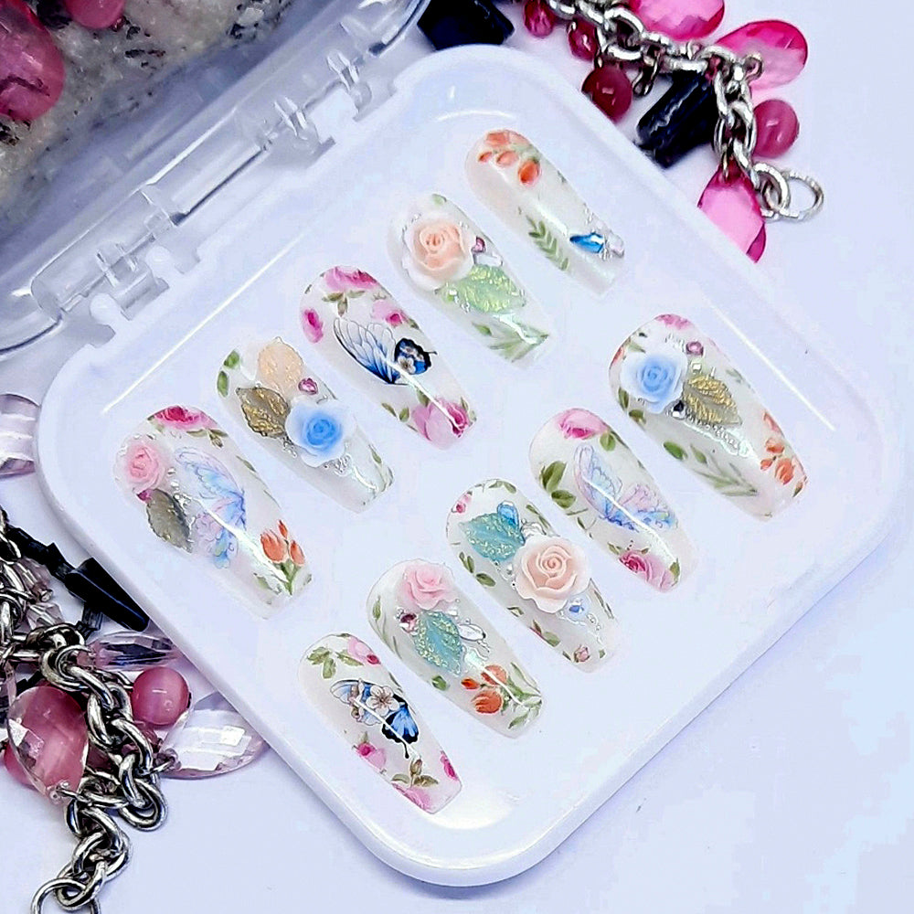 Beautifully romantic press on nails in milky white with subtle chrome; decorated with flowers, butterflies, and some beautiful 3d roses, leaves, pearls, gems and beads. Finished in gloss top coat.