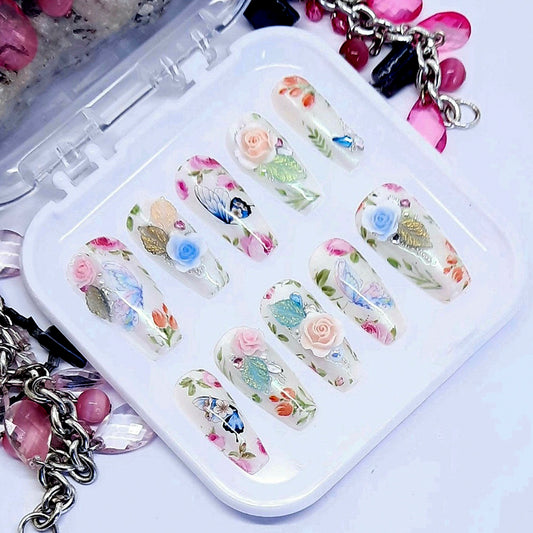 Beautifully romantic press on nails in milky white with subtle chrome; decorated with flowers, butterflies, and some beautiful 3d roses, leaves, pearls, gems and beads. Finished in gloss top coat.