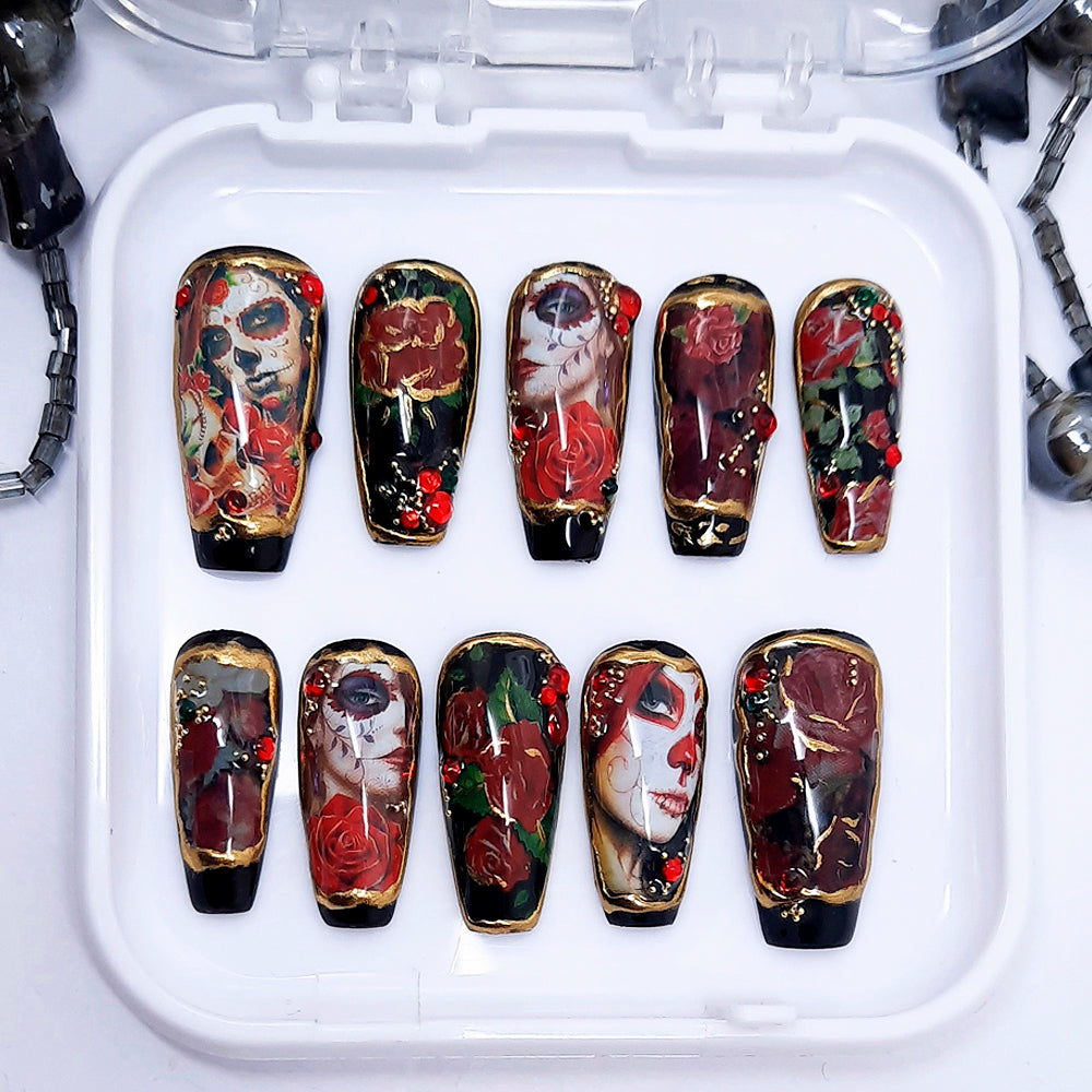 A set of black press on nails with a Day of The Dead design, including red roses, 3d nail art and gold chrome. Finished in gloss top coat.