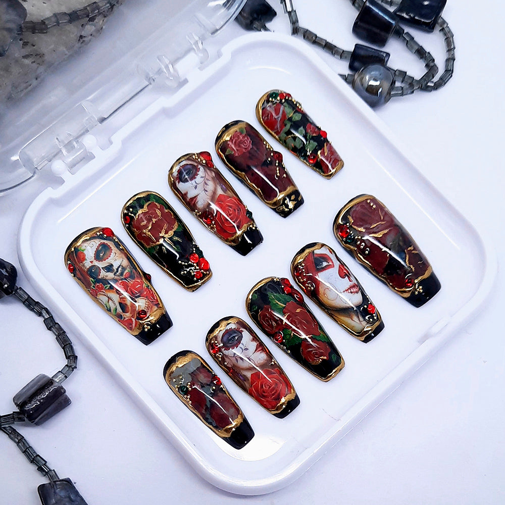 A set of black press on nails with a Day of The Dead design including red roses, 3d nail art and gold chrome. Finished in gloss top coat.