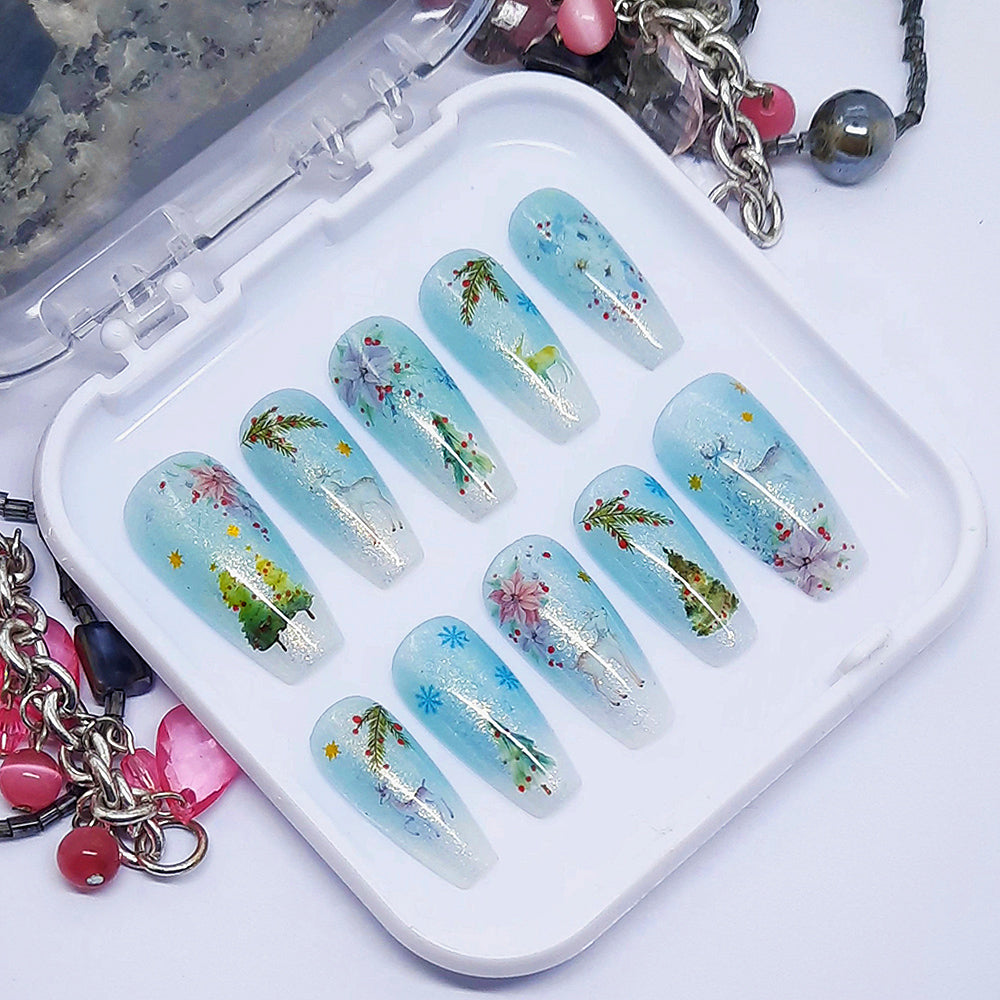 A set of press on nails in blue and white with a Christmas themed design, displayed in a white tray on a white background.
