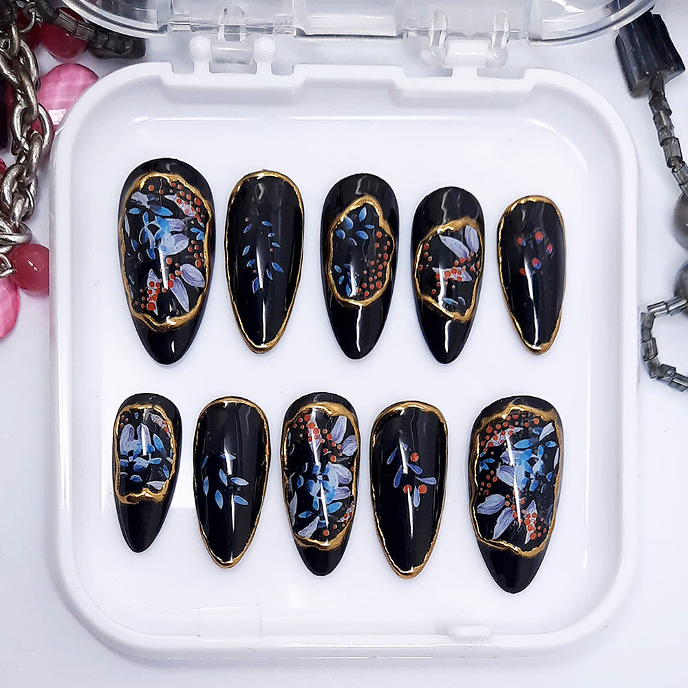 Set of black nail art with floral designs on a white tray.