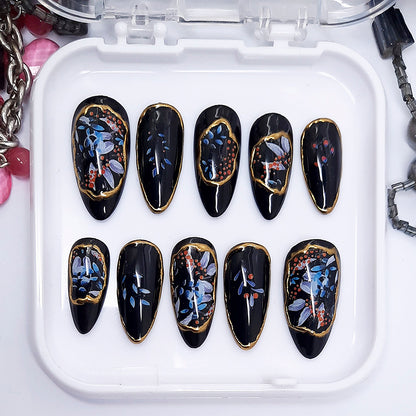 Set of black nail art with floral designs on a white tray.
