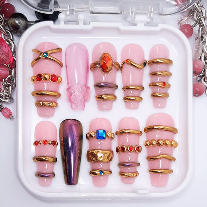 Set of pink and gold nail art designs in a clear case with jewelry items around.
