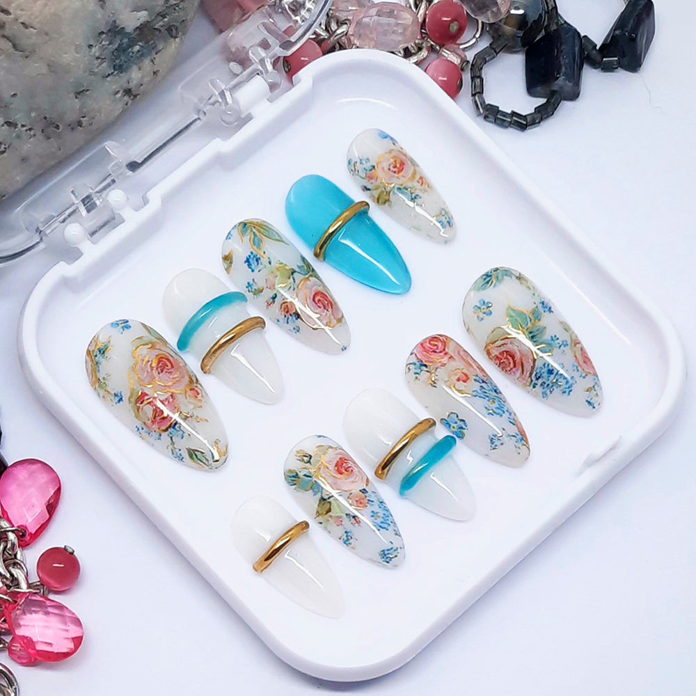 Set of decorative nail art tips with floral designs on a white tray.