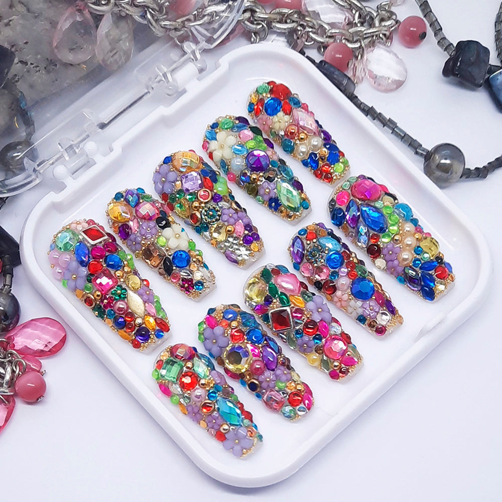 A set of colourful and elaborate press on nails displayed in a tray on a white background.