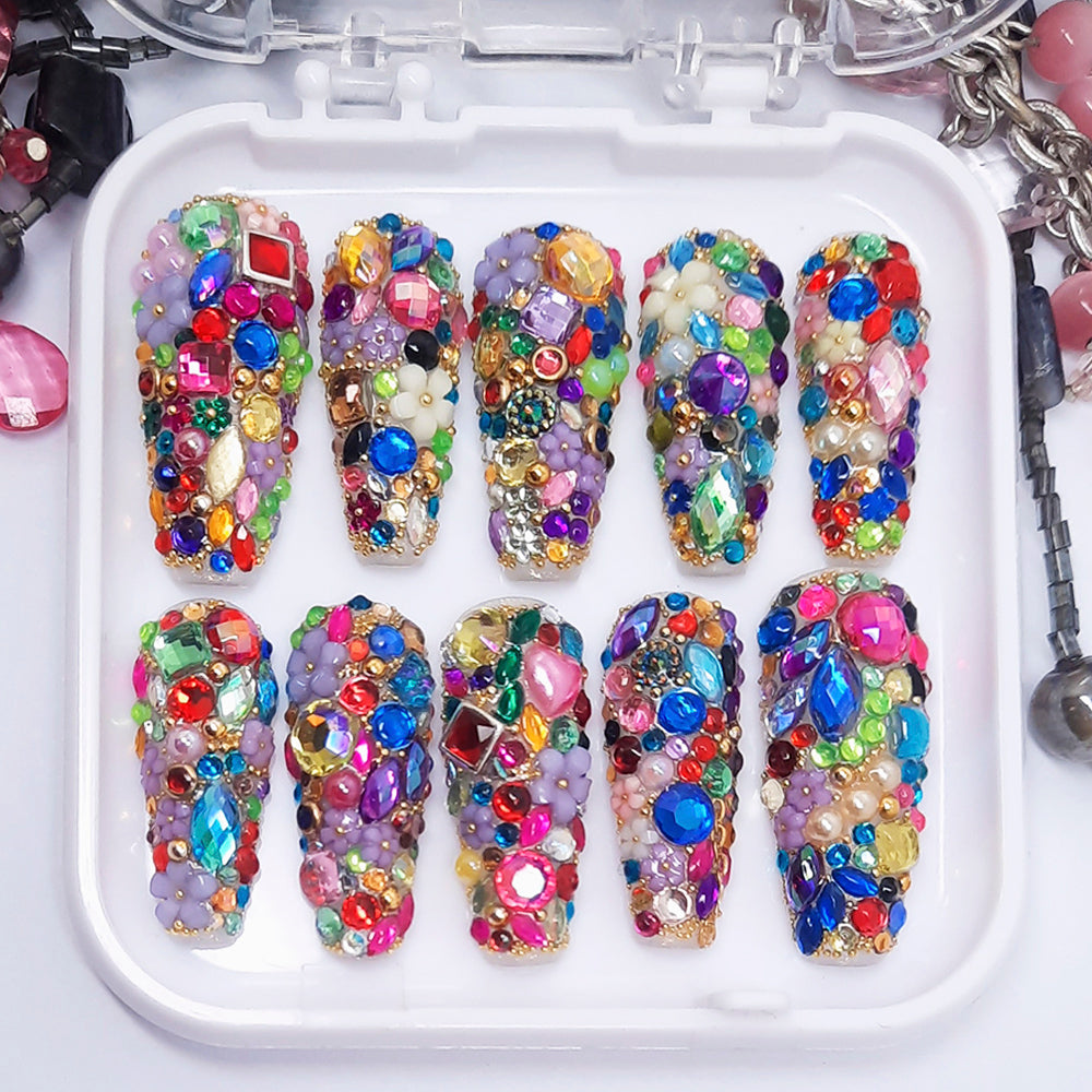 A set of colourful and elaborate press on nails displayed in a tray on a white background.