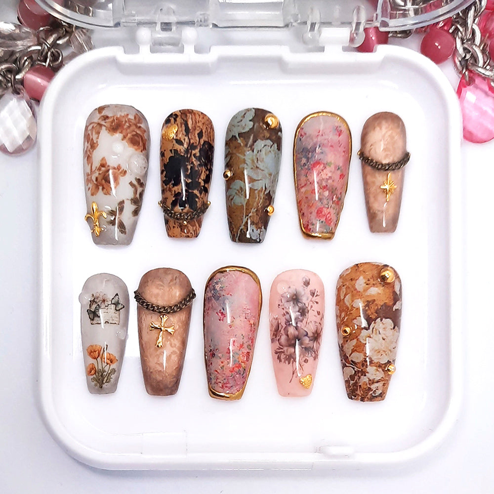 A set of decorative press on nails in a brown floral design displayed in a white tray.