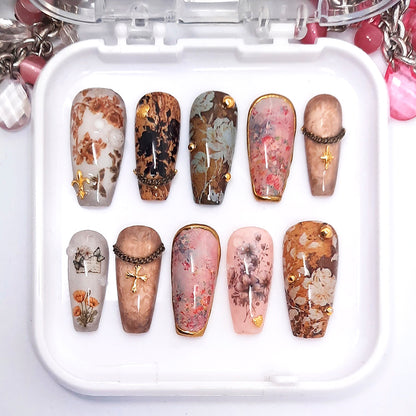 A set of decorative press on nails in a brown floral design displayed in a white tray.