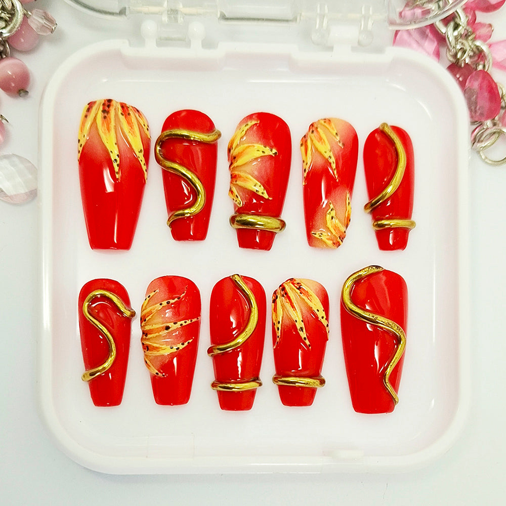 Red nail art with gold accents on a white tray