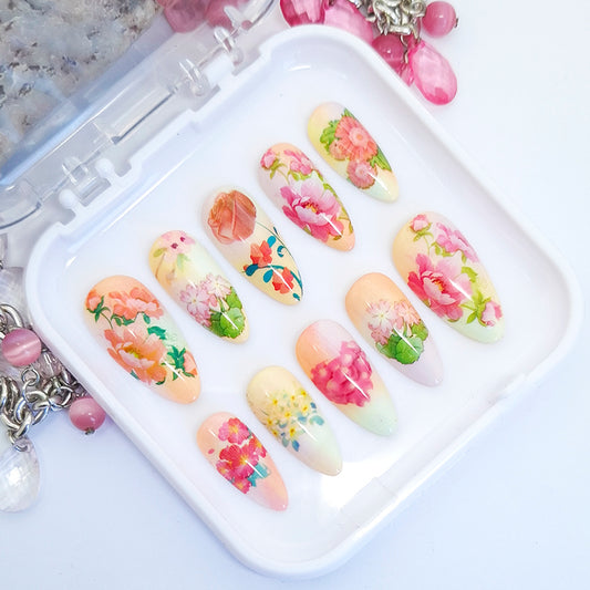 A set of nail tips with a colourful floral design displayed in a white tray.