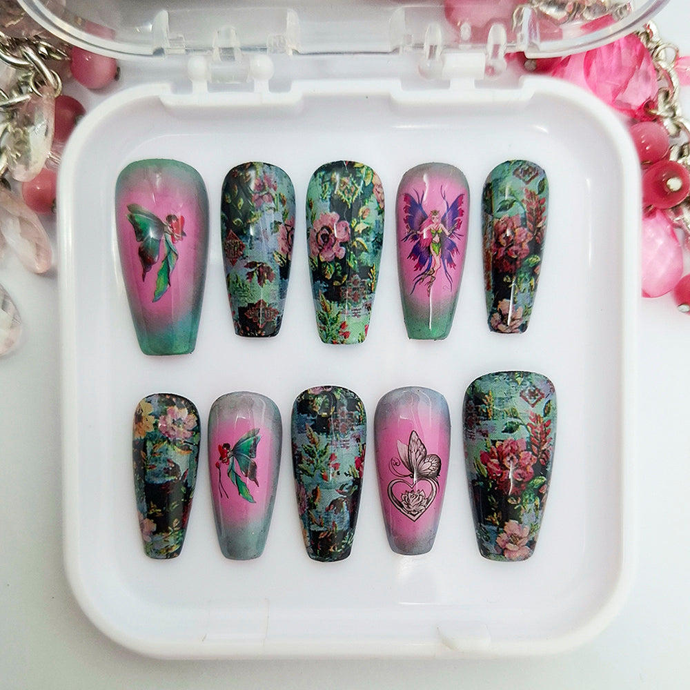 A set of hand made press on nails in pink, blue and green shades with a design of flowers, fairies and a butterfly. Displayed in a white tray on a white background.
