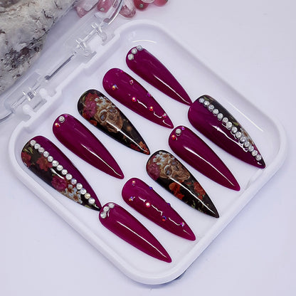 stunning press on nails in a fuchsia gel polish with skulls, flowers and crystals