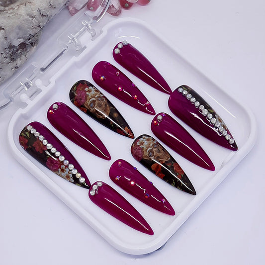 stunning press on nails in a fuchsia gel polish with skulls, flowers and crystals