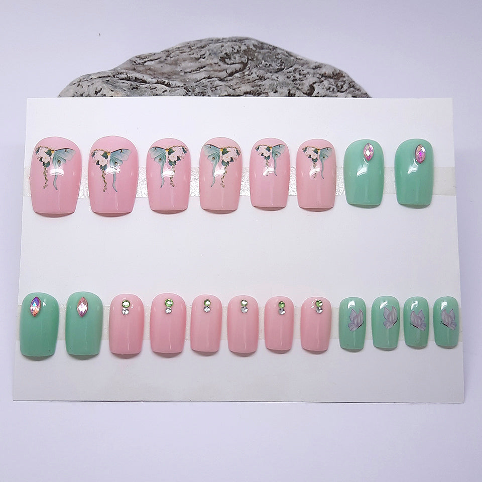 a full set of 20 nails in this pretty one size fits all press on set. Soft pink and green, with butterflies and gems.