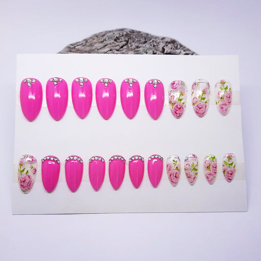 Set of pink and floral nail designs on a white card with a gray surface underneath.